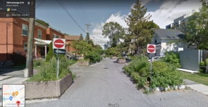 Google streetview of Cambridge North in Ottawa. We can see concrete planter boxes used to narrow the street and add greenery. There are two "do not enter" signs to divert car traffic from entering from the main street and car traffic volumes lower.