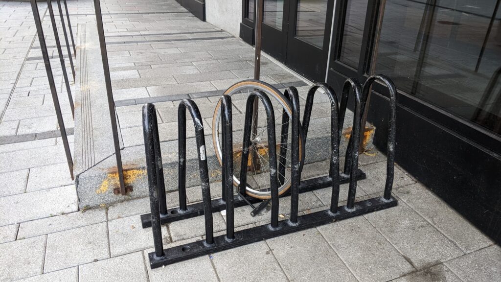 Picture of a wheel well rack with a wheel still locked by a U-Lock, while the rest of the bicycle has clearly been stolen while parked at this rack.