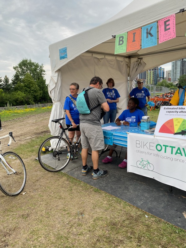 Volunteers at Bluesfest bike parking registration tent attending to people bringing in their bikes