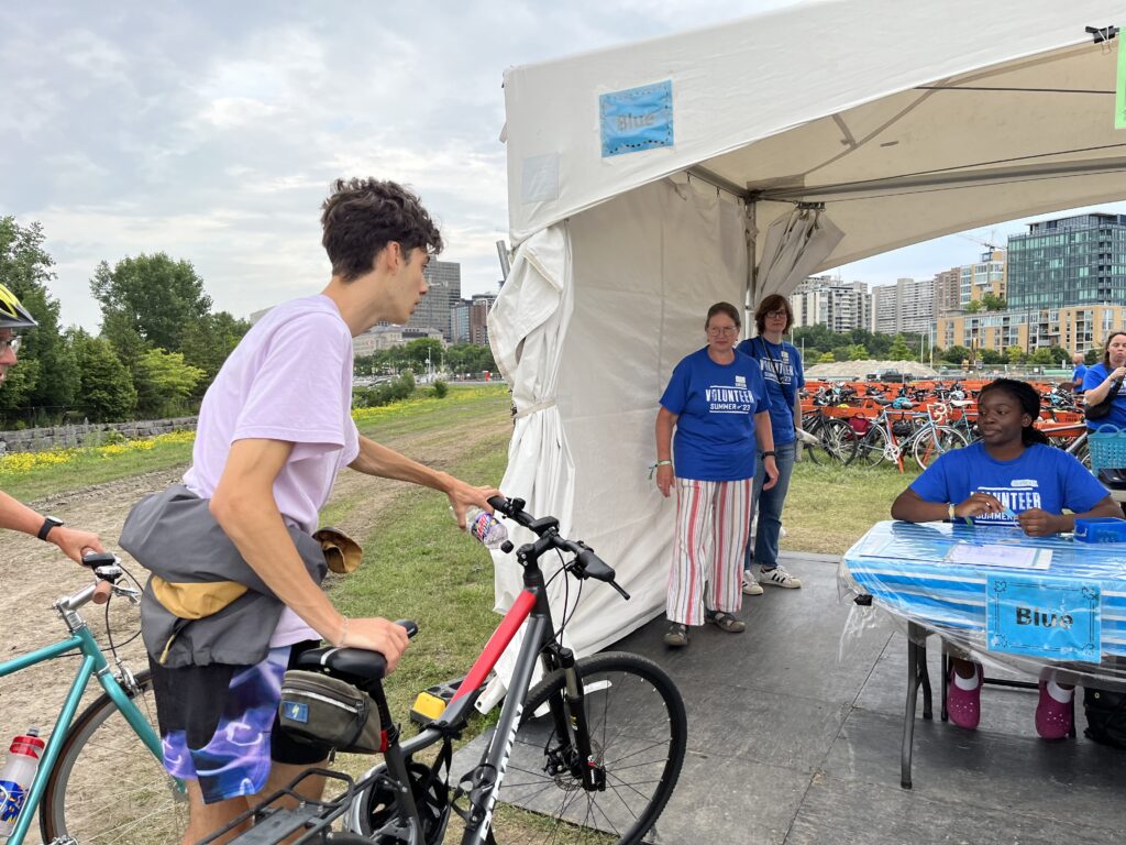 Volunteers at Bluesfest bike parking registration tent attending to people bringing in their bikes.